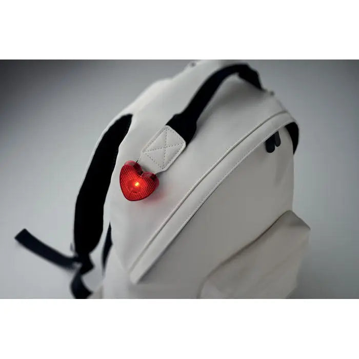 Lumina reflector in forma de inima rosu led atasat pe spatele unei genti albe cu bretele negre
