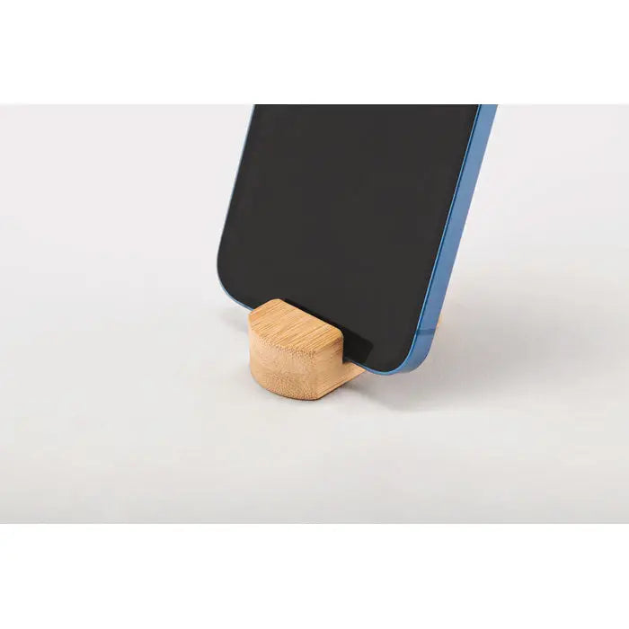 Mini suport pentru telefon din bambus maro deschis tinand un smartphone albastru