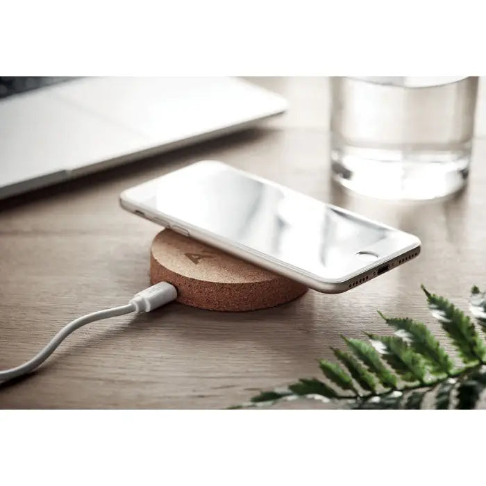 Smartphone argintiu odihnindu-se pe pad de incarcare wireless 10w rotund din plută cu logo subtil gravat