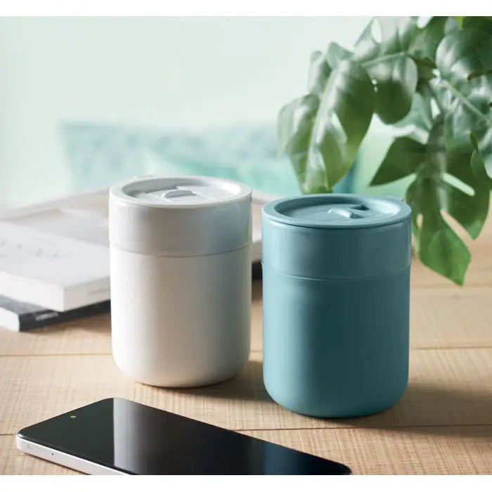 Două recipiente cilindrice izolante pentru alimente pahar ceramic 330 ml mate, una albă și alta teal, pe lemn