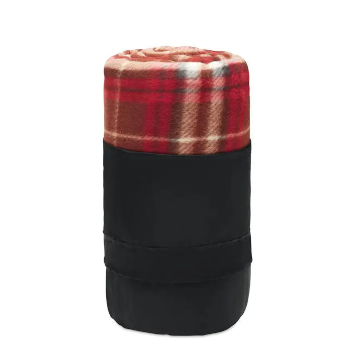 Patura de calatorie din lana rpet in carouri rosu si bej rulata si fixata intr-o husa neagra din material textil