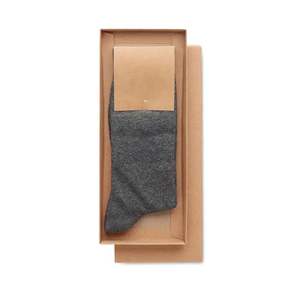 O pereche de sosete gri inchis din tricot texturat prezentate intr-o cutie cadou maro minimalista