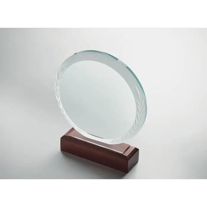 Placa rotunda de premiu din sticla clara cu model gravat de frunze pe margine, montata pe baza din lemn intunecat lustruit