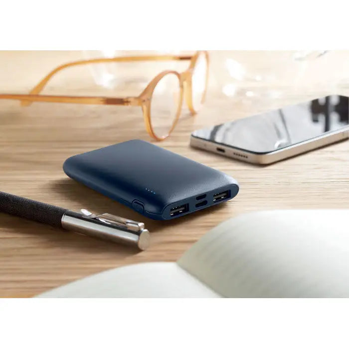 Power bank portabil dreptunghiular albastru închis cu 5000 mAh și suprafață texturată cu multiple porturi usb