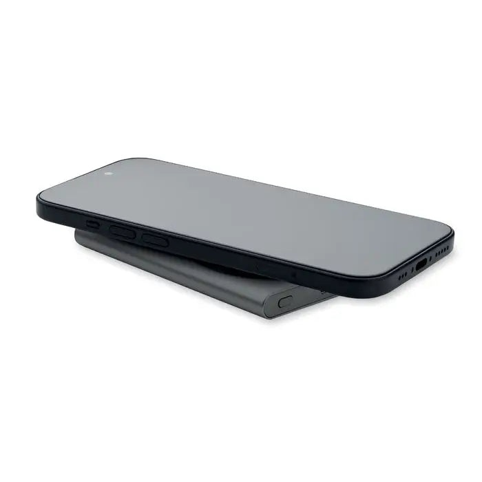 Smartphone negru odihnindu-se pe un incarcator wireless mat cu aspect elegant pentru power bank incarcator wireless