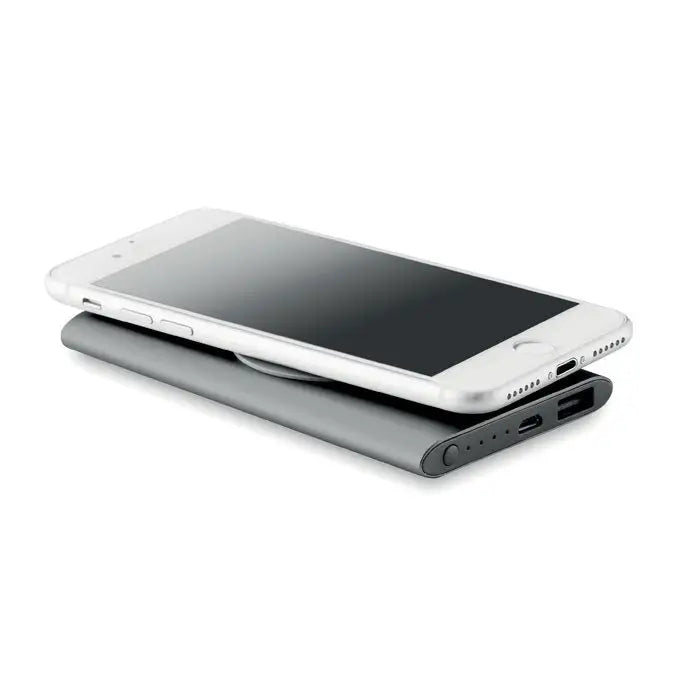 Iphone argintiu așezat pe un power bank wireless 4000mAh negru mat cu porturi usb și lumini indicatori vizibile