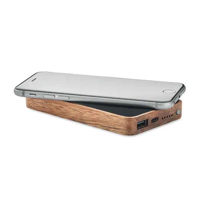 Un telefon inteligent argintiu elegant așezat pe un power bank wireless dreptunghiular din lemn cu 4000 mAh