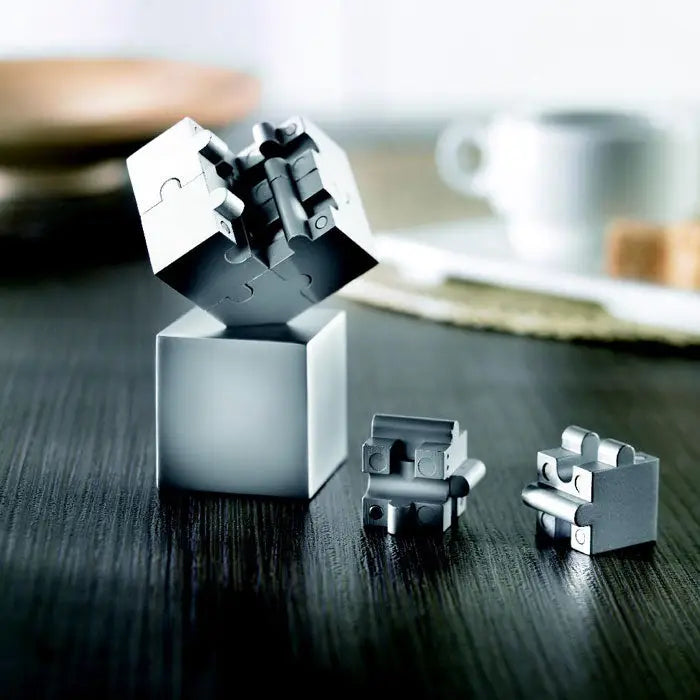 Puzzle metalic 3d cub din piese mecanice argintii intercalate cu design minimalist si finisaj metalic
