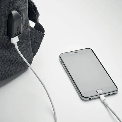 Un iphone 6s plus argintiu elegant conectat la cablu de incarcare pe o suprafata alba langa un rucsac din poliester 600D