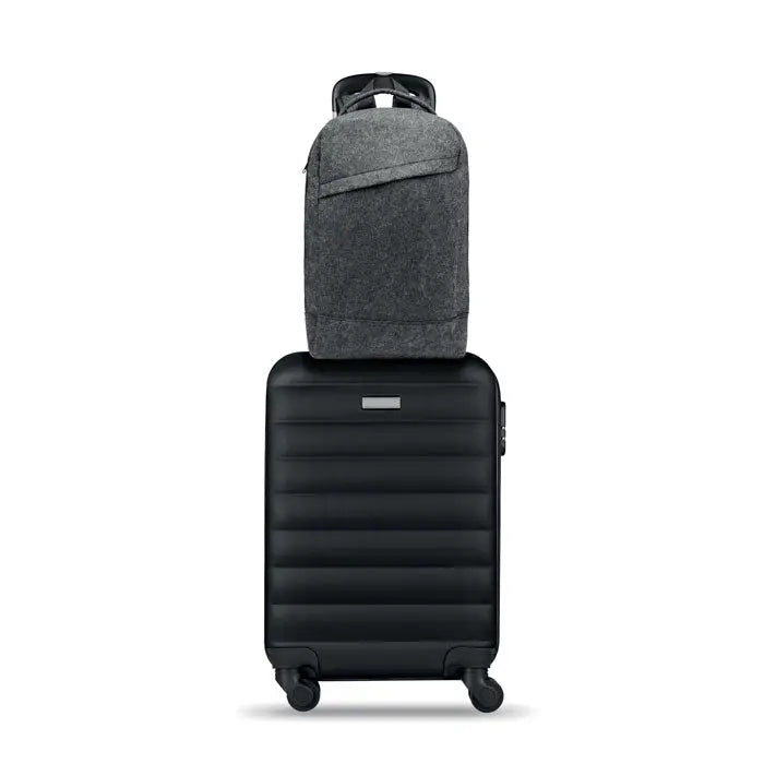 Rucsac pentru laptop de 13 inchi din material texturat gri inchis asezat pe o valiza neagra rigida