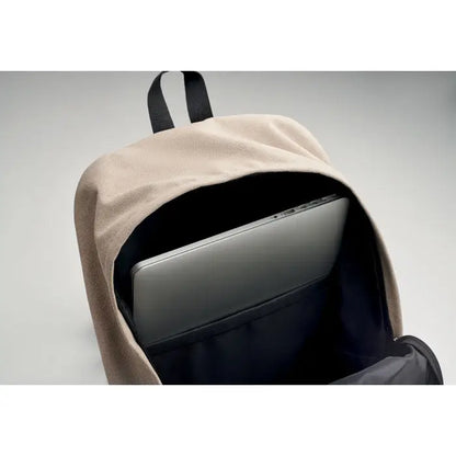 Rucsac pentru laptop de 15 inchi din pânză bej cu interior și bretea neagră, ținând un laptop argintiu