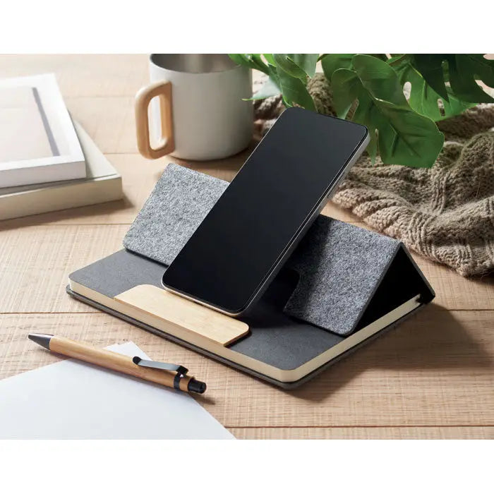 Smartphone negru pe suport din fetru gri si lemn set caiet A5 RPET pentru birou sau acasa