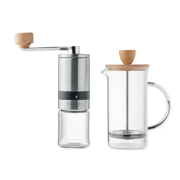 Set de cafea cu râșniță de cafea argintie și sticlă cu mâner de lemn lângă presă franceză clară cu capac de lemn