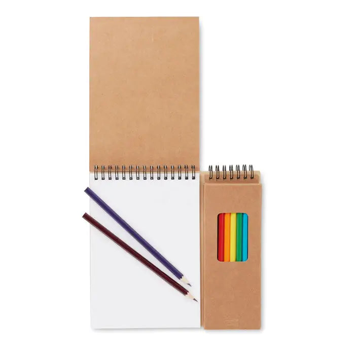 Set de colorat cu bloc de note spiralat din hartie kraft maro cu pagini albe si doua creioane colorate langa acesta