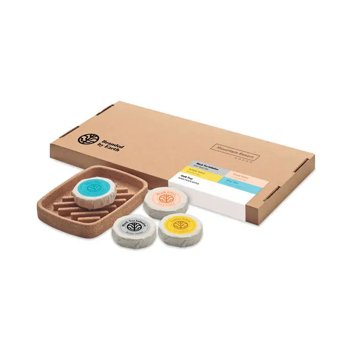 Set de frumusete cadou vegan cu patru sapunuri circulare eco prietenoase in culori albastre, portocalii, galbene si gri pe suport de plută