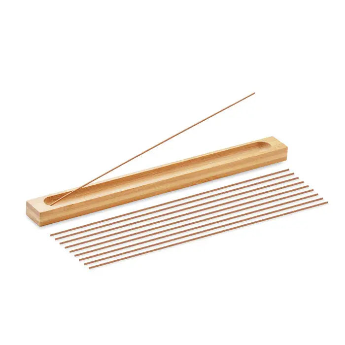 Set de tamaie din bambus cu suport maro deschis și un băț aprins aliniat lângă zece bețișoare suplimentare