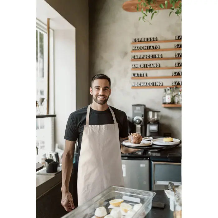 Apron bej din bumbac reciclat purtat de barista într-o cafenea