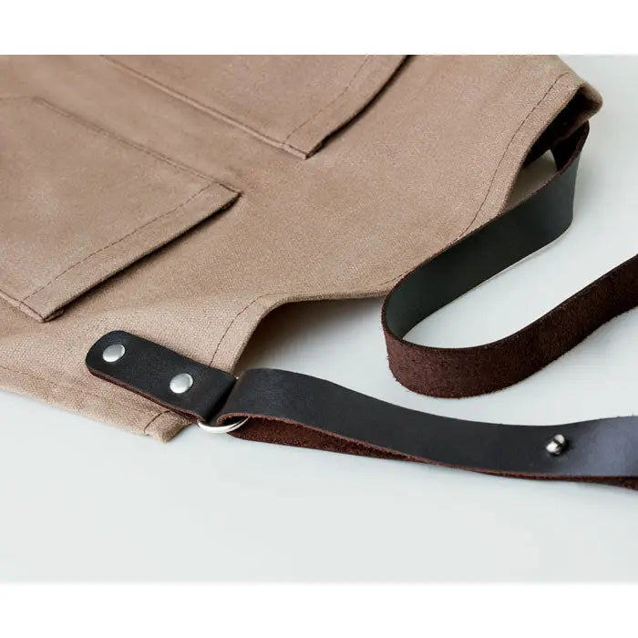 Sort din piele tan canvas apron with black leather straps and silver rivets for durable use