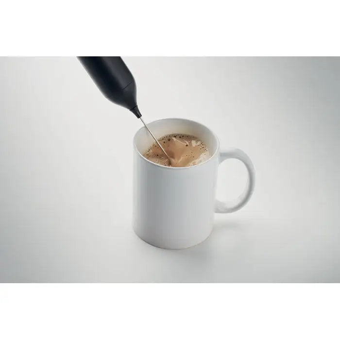 Spumator electric pentru lapte negru din plastic în utilizare deasupra unei cești ceramice albe
