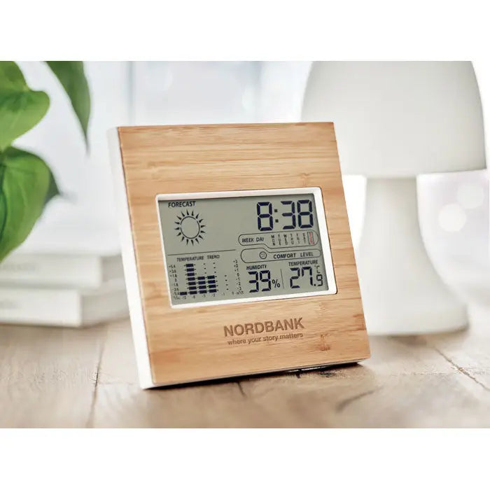 Statie meteo fata din bambus nordbank cu finisaj lemn deschis si baza alba afiseaza ora temperatura umiditatea si prognoza