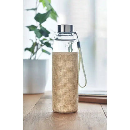 Sticlă de sticlă de 500 ml cu capac metalic argintiu și curea verde deschis în husă de in bej texturat