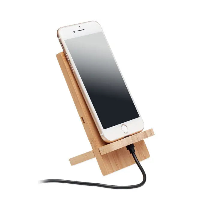 Suport pentru incarcare wireless 10w din bambus deschis la culoare tinand un iphone alb cu cablu de incarcare conectat