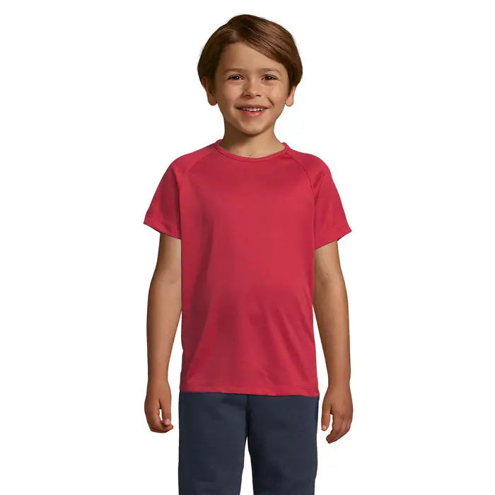 Copil purtând un tricou sportiv roșu vibrant cu mâneci raglan din bumbac 140g trioc sporty pentru copii