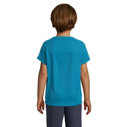 Un copil poartă un tricou sportiv vibrant teal cu mâneci raglan din material 140g trioc pentru copii