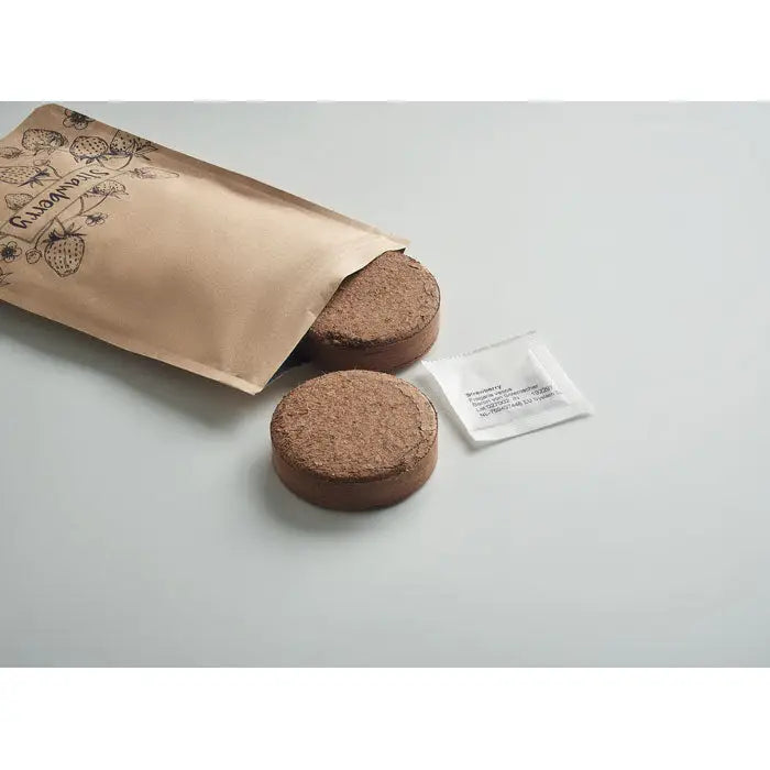 Două ghivece rotunde maro din coir de cocos lângă o punga kraft deschisă etichetată capsuni și un plic mic alb