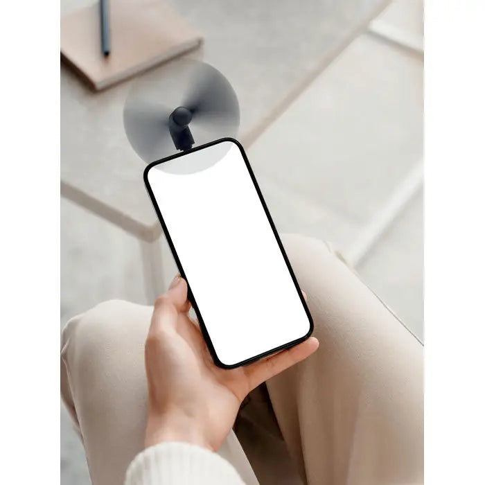 Telefon mobil cu rama neagra si ecran alb gol tinut in mana pentru utilizare cu ventilator portabil usb-c